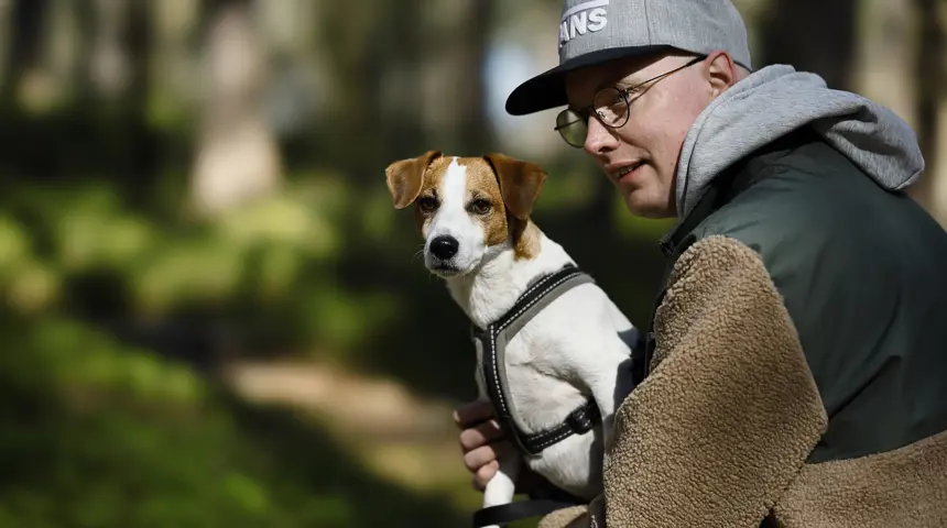 Mattias i skogen med hunden Enzo i knät.